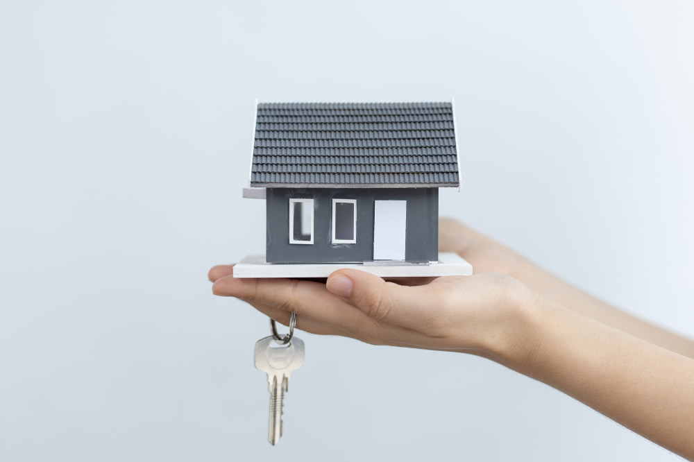 Person holding keys and a mini house