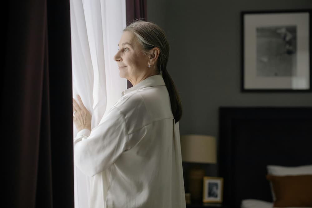 Older women standing next to her pension property window